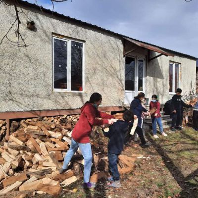 The children help with stacking firewood.